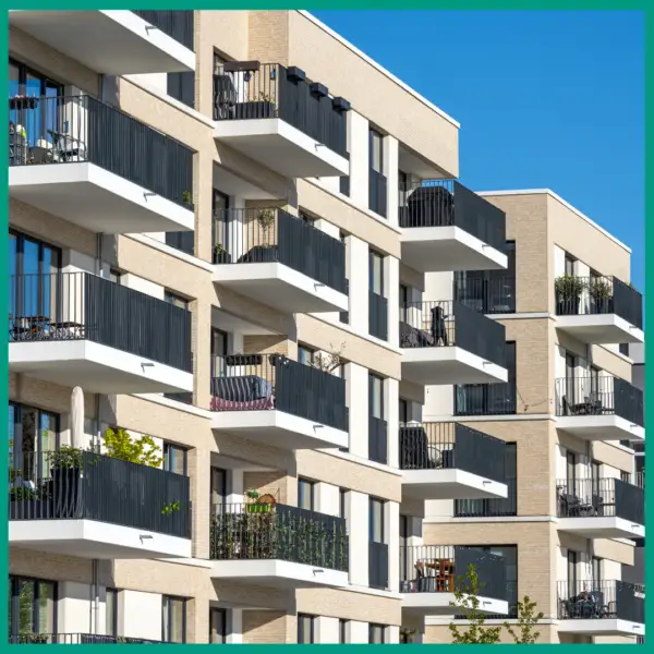 Facade of a modern apartment building with spacious balconies and black railings, on a sunny day
